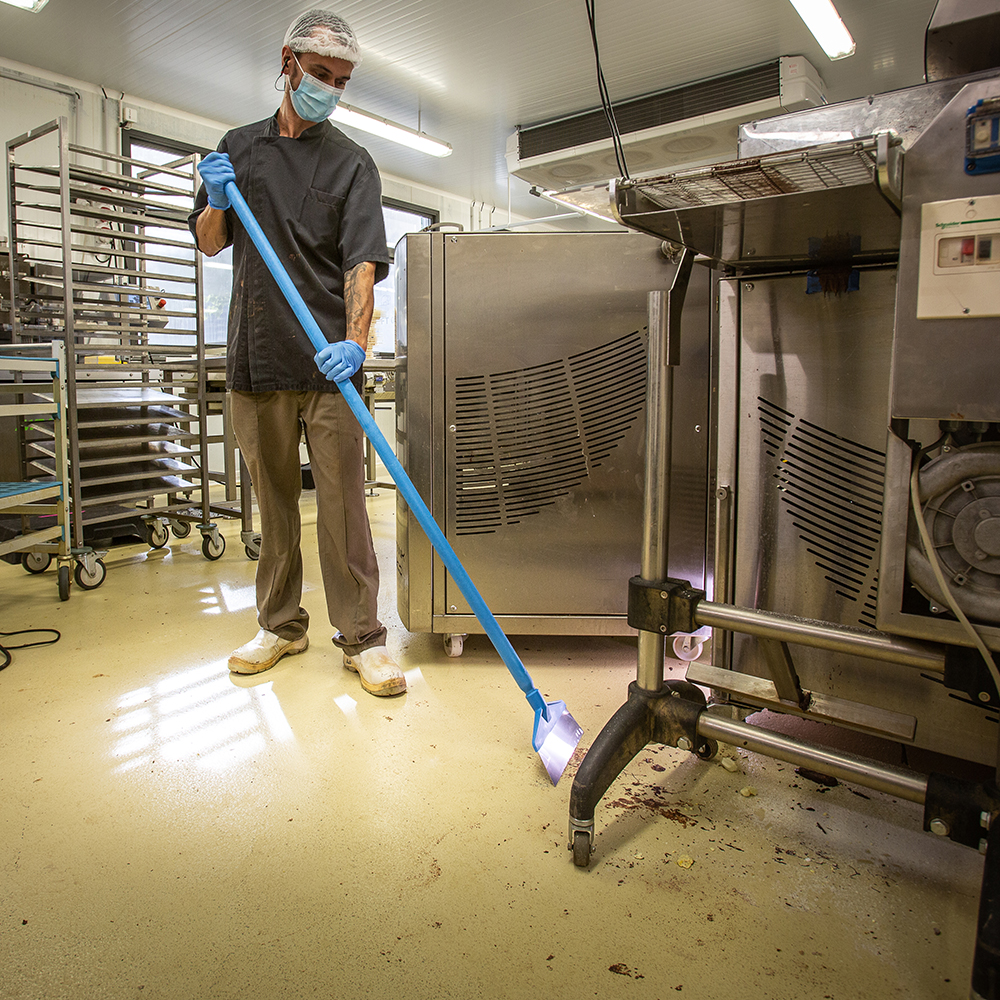 Close-up of a Vikan floor squeegee effortlessly removing dirt and residues from a factory floor, suitable for the food industry.