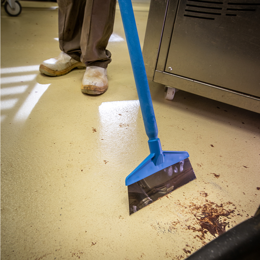 Close-up of a Vikan floor squeegee removing food residues, ideal for HACCP-compliant cleaning in hygienic environments.